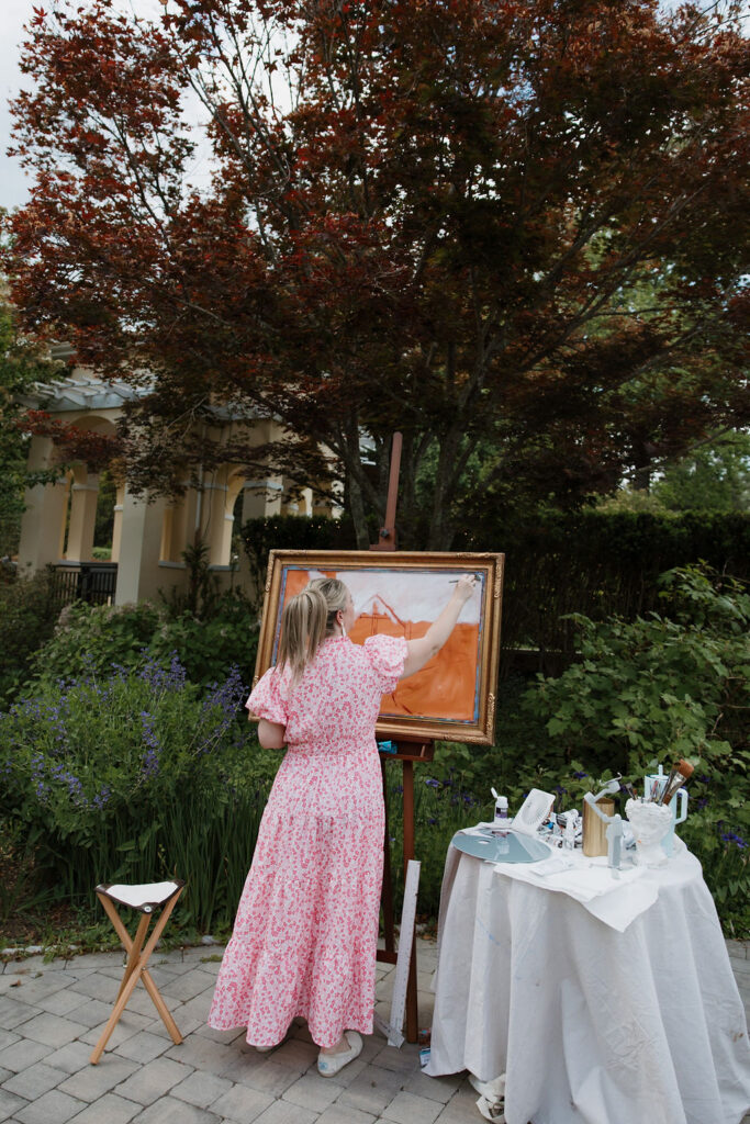 A wide shot of live wedding painter, Brittany Branson, at work on the beginnings of her painting.