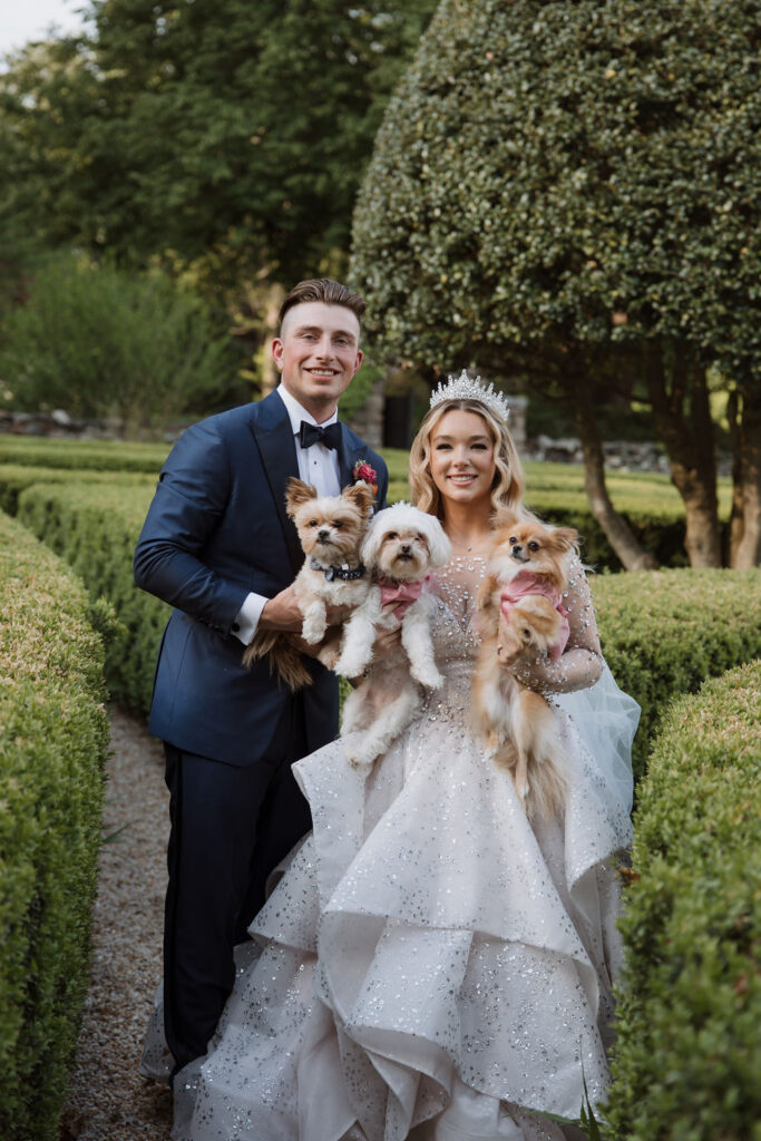 A wedding portrait of Baylen and Colin as they hold their three dogs, Fluffy, Tootsie, and Pumpkin.