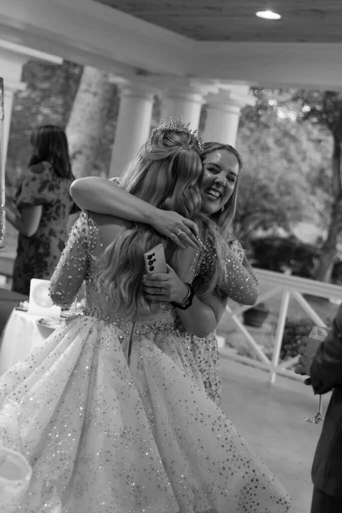 A black and white photo of Baylen hugging live wedding painter, Brittany Branson.